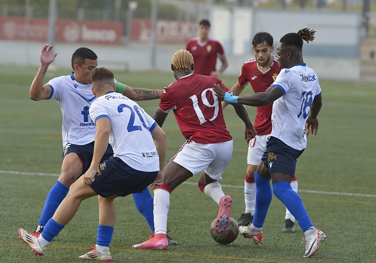 Kayode, rodeado de rivales, ayer en el Campus de Espinardo.