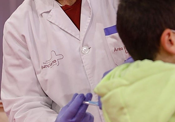 Un enfermero poniendo una vacuna a un niño, en una foto de archivo.