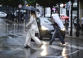 Peatones se protegen de la lluvia al caminar por el centro de Murcia, en una imagen de archivo.