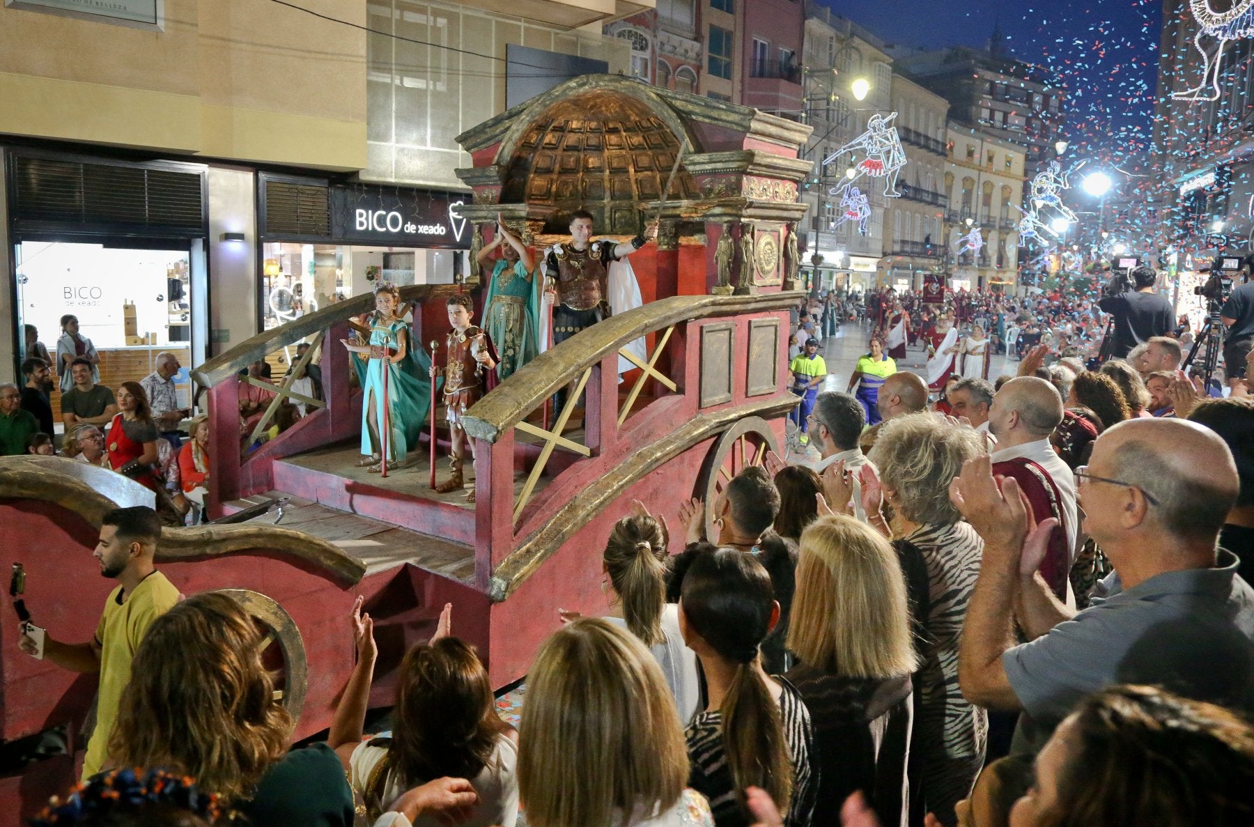 Escipión y Emilia Paula saludan al público congregado en Puerta de Murcia desde su carroza inspirada en el Panteón de Roma.