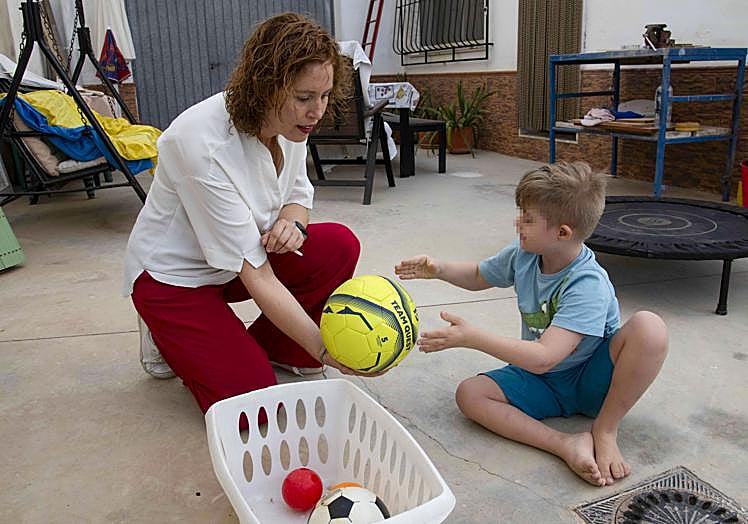 Elena Fernández, portavoz de la plataforma 'Ningún niño sin ATE', juega con su hijo Álex en casa.