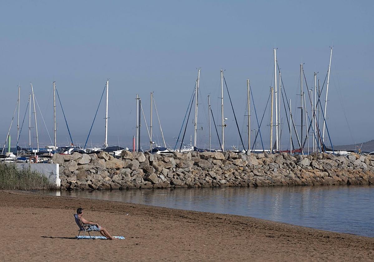 Un hombre toma el sol junto a los barcos amarrados en Mar de Cristal.