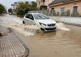 Un vehículo atraviesa la carretera de Churra, en Murcia, anegada de lluvia.