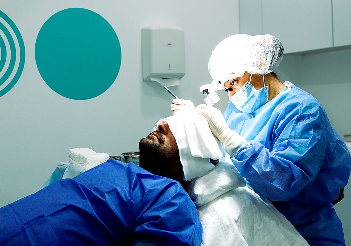 Una especialista de Hospital Capilar realiza un injerto capilar a un paciente.