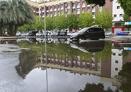 Un coche circula por un parking de Murcia anegado por las lluvias de la semana pasada.