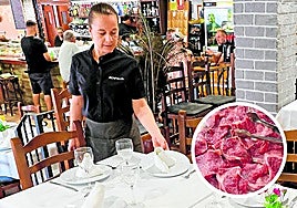 Una de las camareras prepara las mesas en el comedor del restaurante.