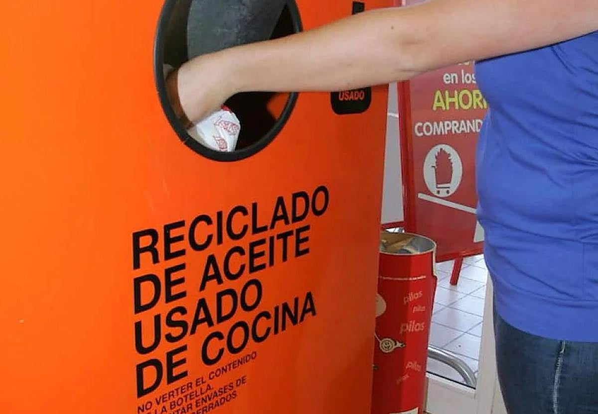Una mujer deposita su aceite usado en uno de los contenedores de recogida de la ciudad.