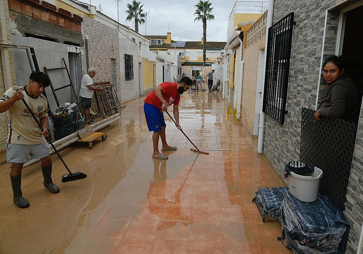 Vecinos de Los Alcázares se afanan en retirar el barro de sus viviendas, este sábado.