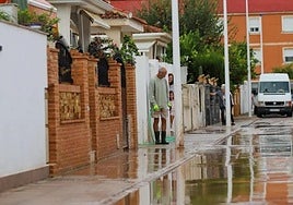 Unos vecinos de San Javier retiran el agua acumulada en su calle.