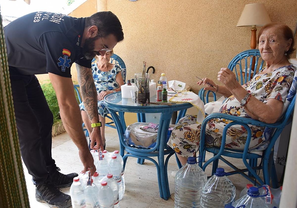 Javier López, de Protección Civil de Los Alcázares, entrega agua a Hilaria y María.
