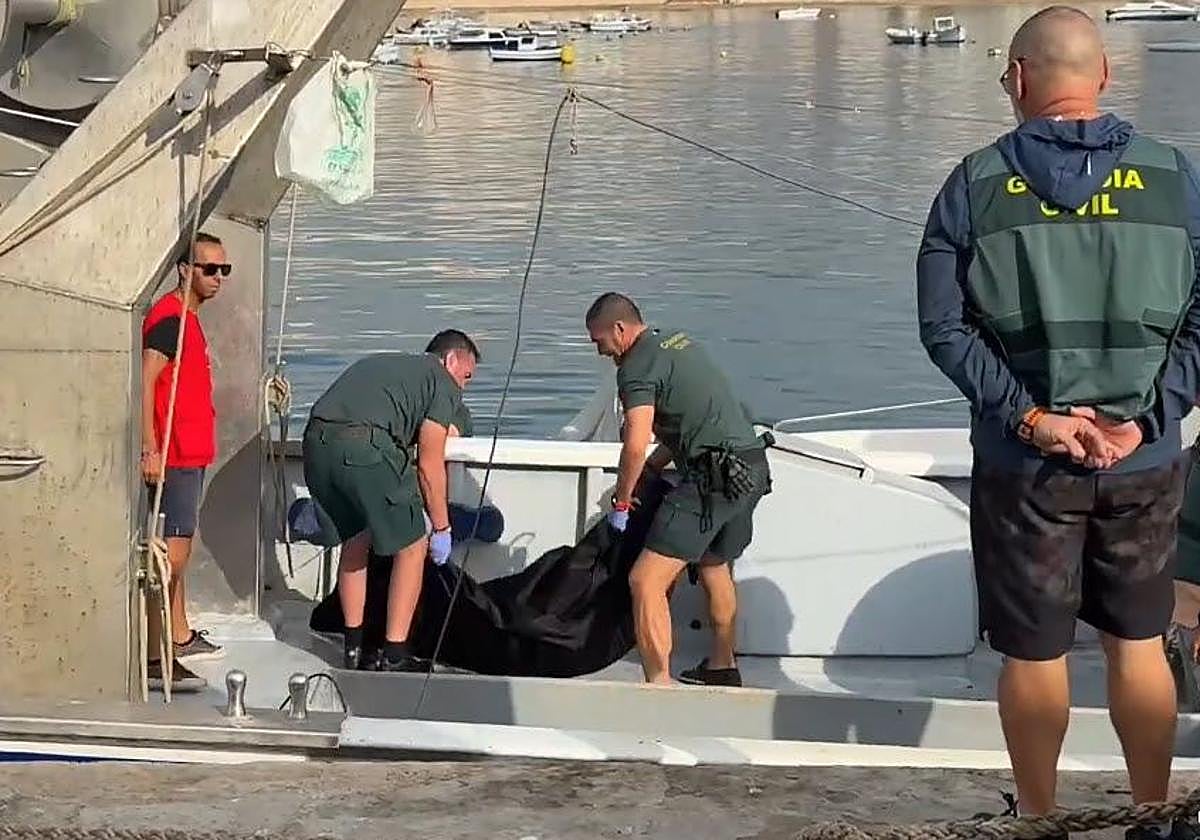 Agentes de la Guardia Civil recuperan el cadáver hallado en el puerto pesquero de Águilas.