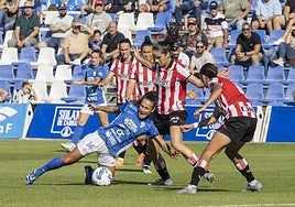 Ana Velázquez, en el suelo, ante dos jugadoras del Athletic.
