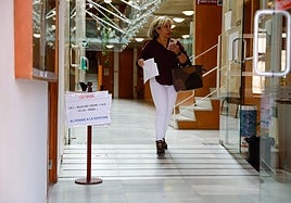 Una ciudadana pasa junto a un cartel informativo sobre el pago de tributos en el Ayuntamiento.