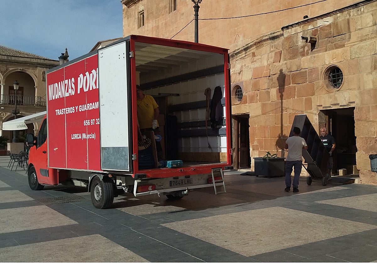 Operarios cargan en el camión de mudanza el mobiliario de la oficina de turismo de la plaza de España.