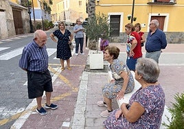 Vecinos de Ojós se reúnen y charlan junto a la iglesia del pueblo, en el que cada vez quedan menos menores de edad.