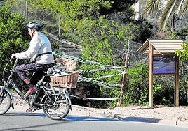 Una ciclista pedalea junto la Cueva del Agua precintada por la Guardia Civil tras la muerte de una mujer este enero.