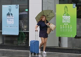 Una mujer se protege de la lluvia por las calles de Murcia.