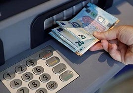 Imagen de archivo de una persona sacando dinero de un cajero.
