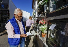 Dos vecinos de Ceutí limpian tumbas de familiares, con el cartel del Ayuntamiento en la mano.
