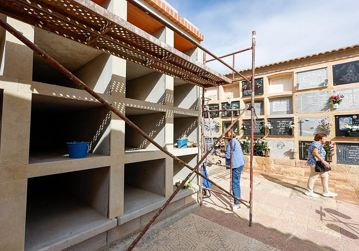 Una mujer con un ramo de flores junto a uno de los bloques de nichos en reconstrucción, ayer.