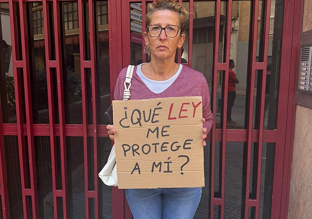 Ana muestra un cartel de protesta en la entrada del edificio donde está su casa ocupada por su inquilina.