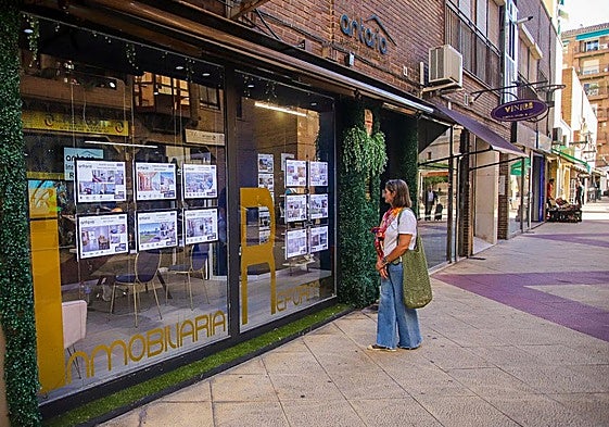 Una mujer observa los anuncios de viviendas en venta en una oficina inmobiliaria en Murcia.