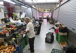 Clientes y placeros en los puestos de frutas y verduras, en uno de los pasillos donde hay más negocios cerrados que en funcionamiento.