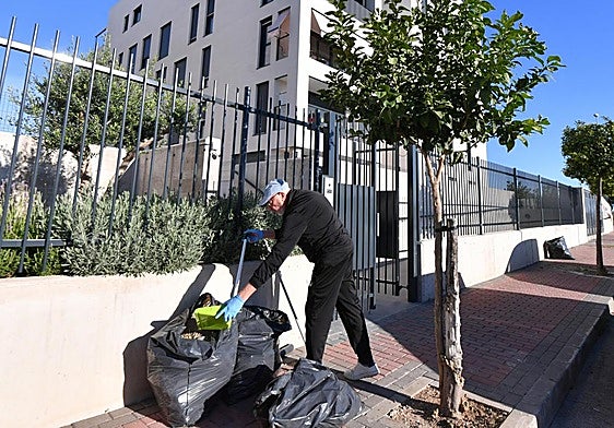 Un vecino de Guadalupe recoge basura y otros restos vegetales frente a su edificio.