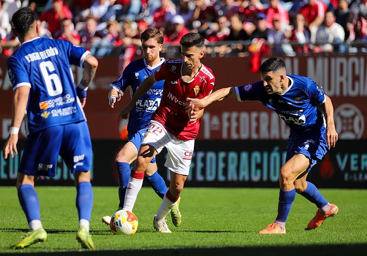 Juan Carlos Real, jugador del Real Murcia, es rodeado por varios futbolistas del CD Teruel.