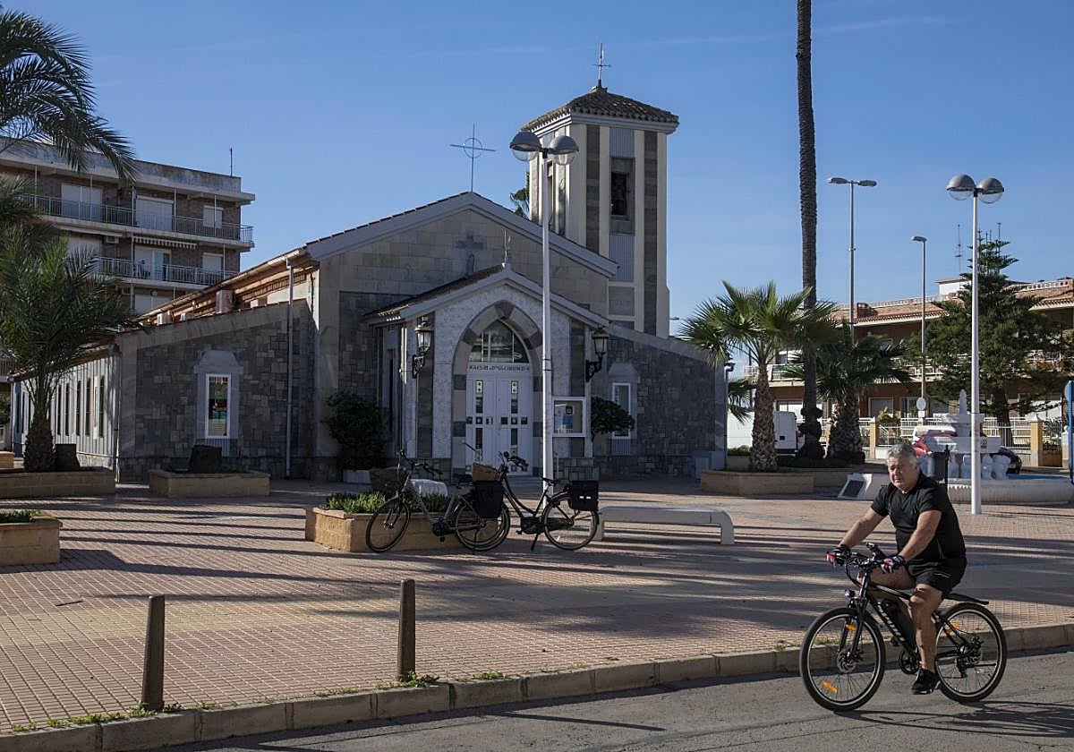 Un vecino pasea con su bici frente a la iglesia de Los Urrutias, ayer.