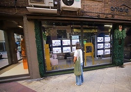 Una mujer revisa los anuncios de viviendas en una inmobiliaria.