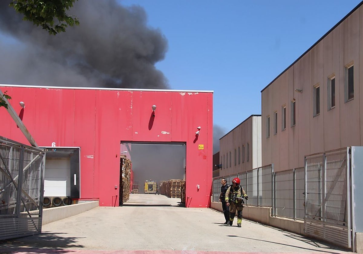 Un policía local y un bombero, junto a una de las naves incendidas el 24 de junio.