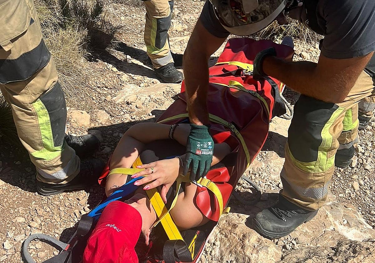 Un bombero coloca a la mujer en la camilla.