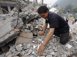 Un hombre busca ente los escombros a su hija desaparecida. /REUTERS