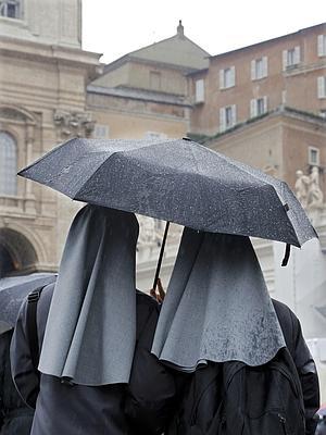 Un par de monjas esperan bajo la lluvia al humo de la chimenea. / Eric Gaillard (Reuters)