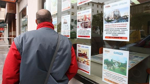 Un transeunte observa las ofertas de una inmobiliaria. 