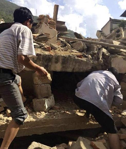 Dos hombres buscan entre los escombros en Yunnan, China.