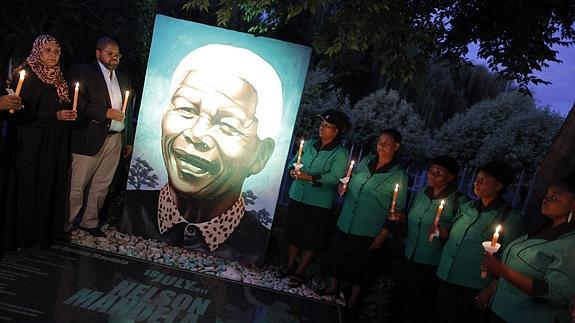 Varias personas encienden velas durante uno de los actos celebrados en honor Mandela. 