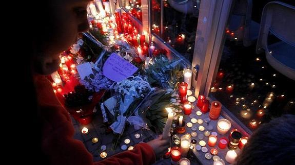 Varias personas depositan flores y velas a las puertas del instituto.