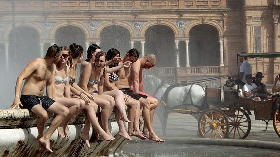 Un grupo de turistas se refresca en la Plaza de España de Sevilla. 