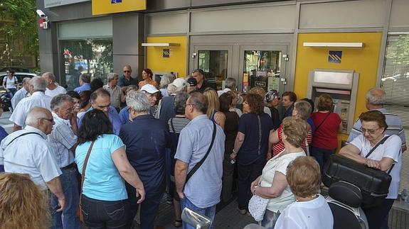 Un grupo de pensionistas hace cola para retirar dinero a la entrada de una sucursal bancaria en Salónica.