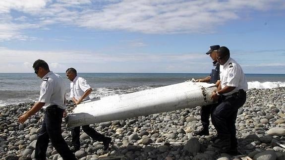 Varios policías llevan el resto de un avión hallado en La Reunión.