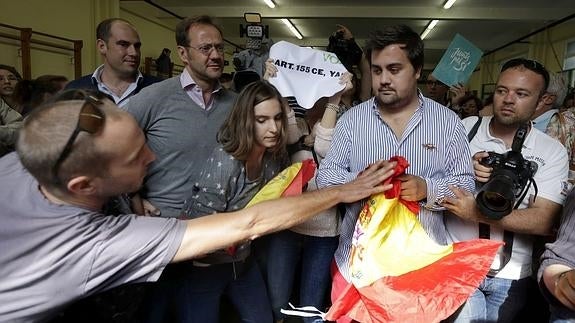 Una persona trata de arrebatar una bandera a un miembro de Vox.