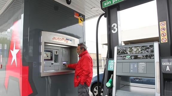 Un conductor pagando en el cajero de una gasolinera autoservicio. 