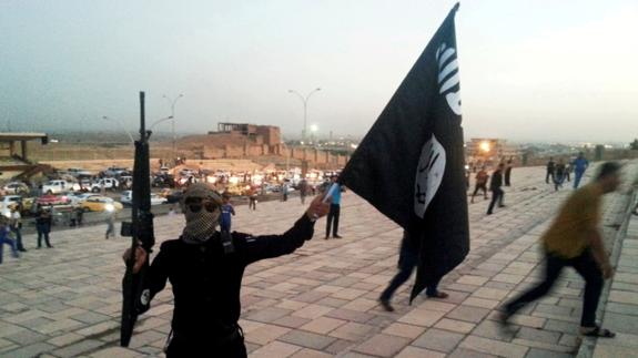 Un combatiente de Daesh muestra una bandera del grupo yihadista en Mosul.