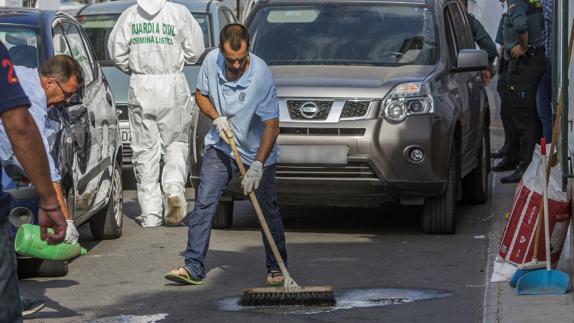 Operarios limpian la sangre de la puerta del domicilio donde fue asesinada la mujer. 