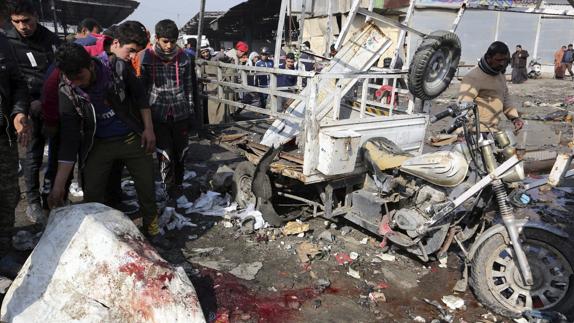 Iraquíes observan restos de sangre junto a un vehículo destrozado.