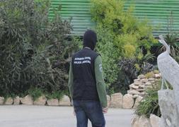 Un policía judicial rastrea el jardín de la vivienda del constructor, pasando junto a la estatua de un pavo real. ::                             GUILLERMO CARRIÓN/AGM