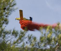 Un avión contra incendios arroja sobre las llamas una descarga de agua mezclada con bentonita, un retardante para el fuego. ::                             JUAN LEAL