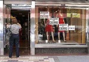 EN LAS ÚLTIMAS. Una señora entra en una tienda de la calle Santa Florentina       con carteles en el escaparate de liquidación por cierre. / P. SÁNCHEZ/AGM